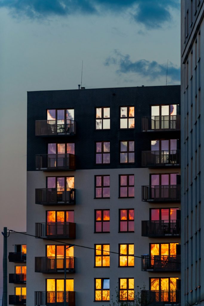 In den Fenstern eines Mehrfamilienhauses spiegelt sich ein farbenfroher Sonnenuntergang.